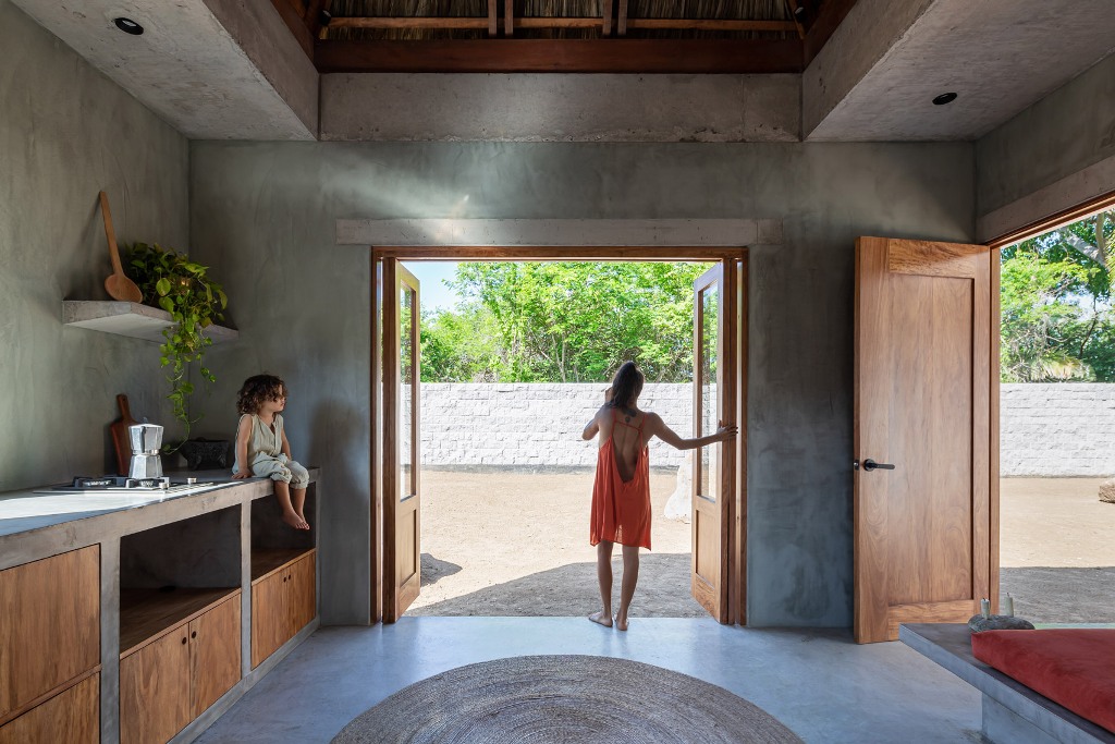 The kitchen is done of concrete, with plywood cabinets and it fully opens to outside