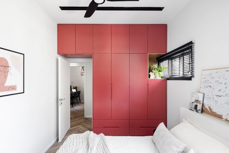 This red accent is a sleek storage unit that takes a whole wall