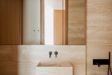 06 The bathroom is also clad with travertine marble, and there’s an oak vanity to echo with the kitchen