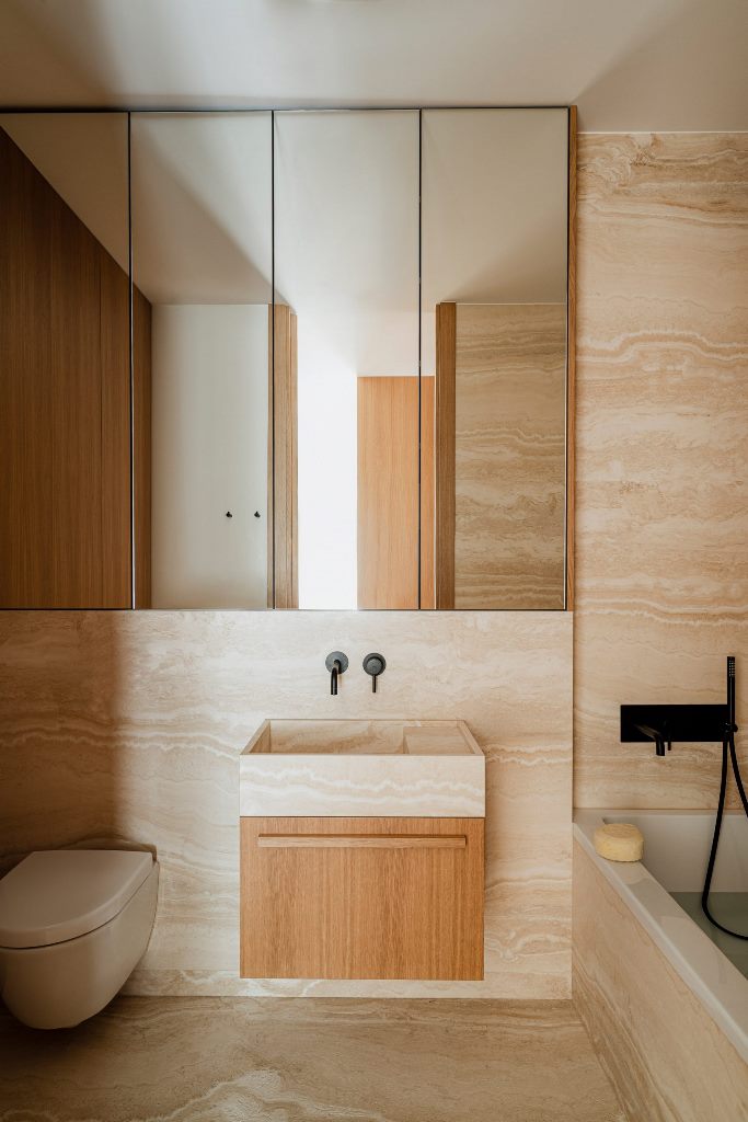 The bathroom is also clad with travertine marble, and there's an oak vanity to echo with the kitchen