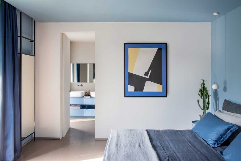 The bedroom features some cool furniture, navy and grey bedding and bold art
