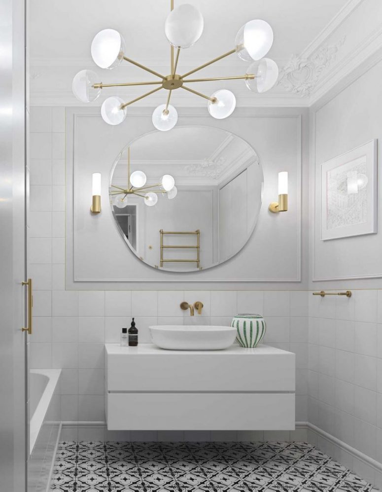 Another bathroom is done in white, with a black and white patterned floor, chic and elegant lamps and brass touches
