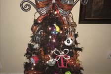 a black Halloween or Christmas tree decorated with Nightmare Before Christmas ornaments, lights, a bow and a giant pumpkin