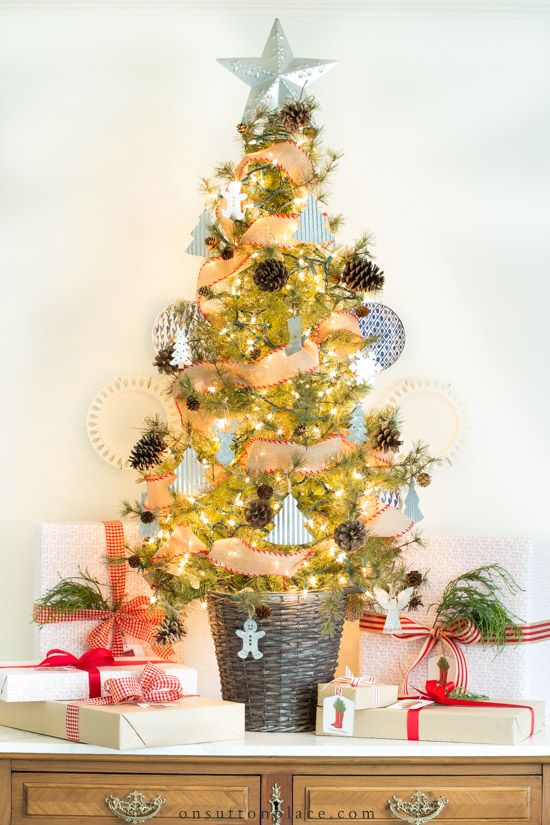 A chic and beautiful Christmas tree in a basket, with pinecones, mini tree shaped ornaments, snowflakes and lights plus a star topper