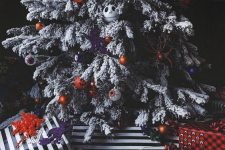 a gorgeous flocked Christmas tree with eyeball, pumpkin and Jack Skellington ornaments and lights plus striped gifts under it
