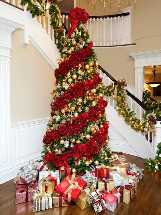 A jaw dropping Christmas tree decorated with red roses and gold ornaments in between floral garlands is magnificent
