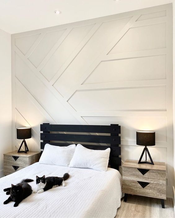 a monochromatic guest bedroom with a white paneled wall, a black bed and neutral nightstands is a chic and bold idea