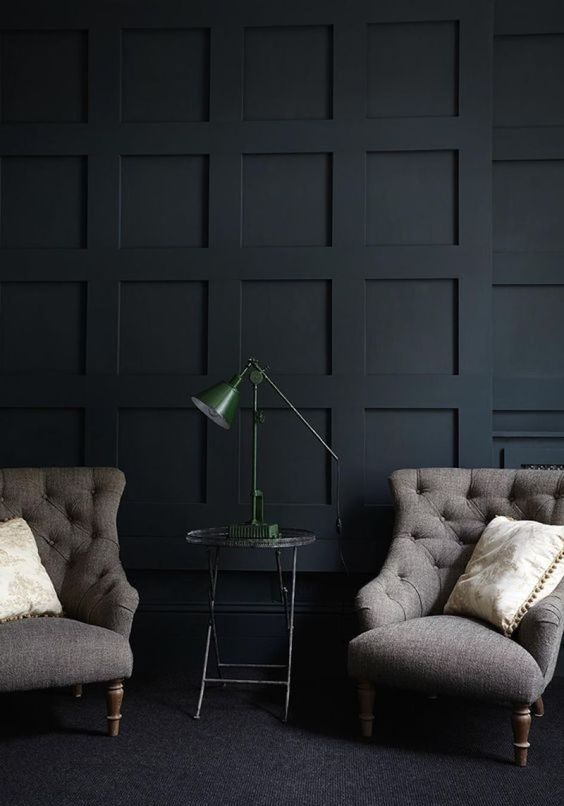 a refined black paneled wall plus vintage furniture create a chic and exquisite mood in this living room