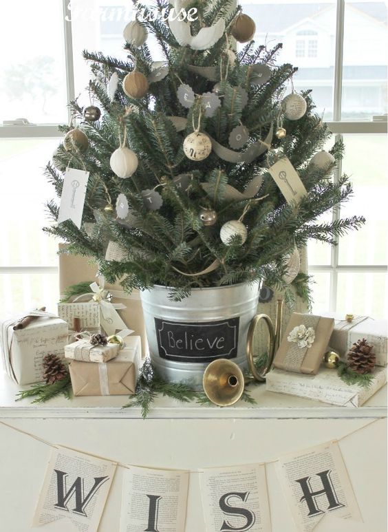 a rustic vintage tabletop Christmas tree decorated with chalkboard and twine and burlap wrapped ornaments, with vintage key prints and some pinecones around