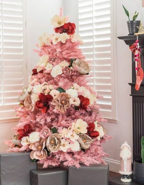 A small pink Christmas tree decorated with white, neutral, red and pink blooms   faux and natural ones for a glam feel