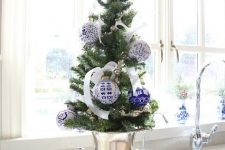 a tabletop Christmas tree in a vintage urn, with white ribbon bows and blue and white Christmas ornaments is a lovely and vintage idea