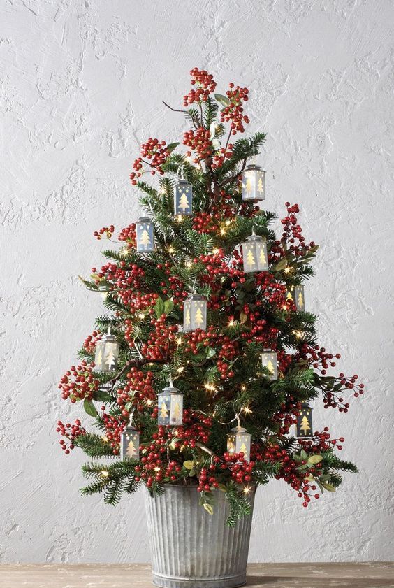 a vintage-inspired tabletop Christmas tree with berries, lights and tree-shaped mini lanterns is a lovely and bold idea