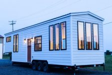 01 This tiny home on wheels is a very simple and clean house, with white facades and a metal roof plus lots of windows