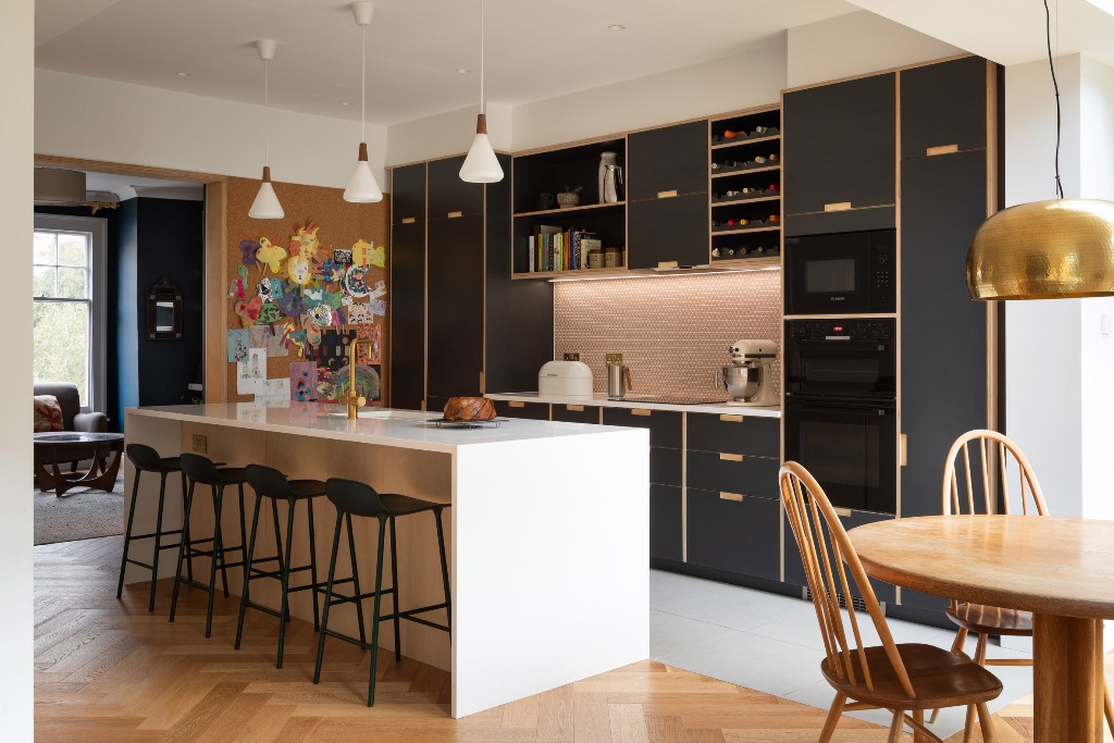 The kitchen features black cabinetry and pink tiles plus pendant lamps
