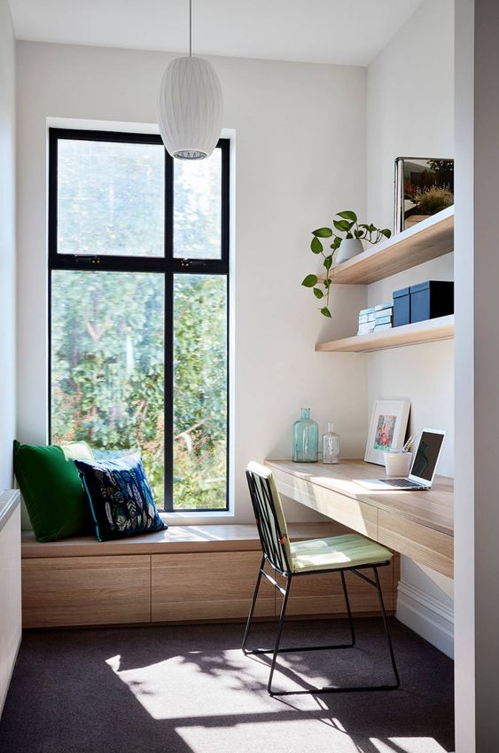 a minimalist home office with a floating desk and a daybed by the window, with open shelves and a comfy chair