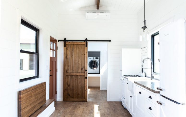 The bathroom is hidden behind a wooden barn door that’s both beautiful and space-efficient