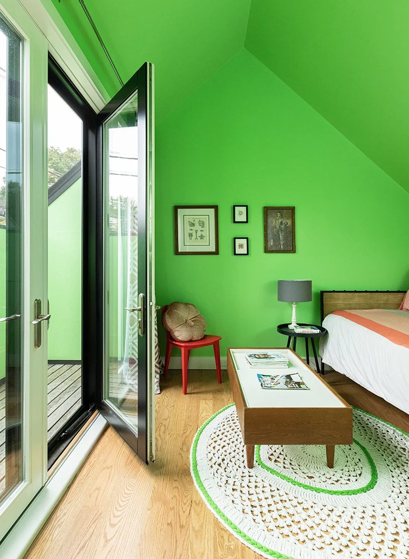 The bedroom is also done with bold green walls and a ceiling, stylish mid-century modern furniture and there's an access to the terrace