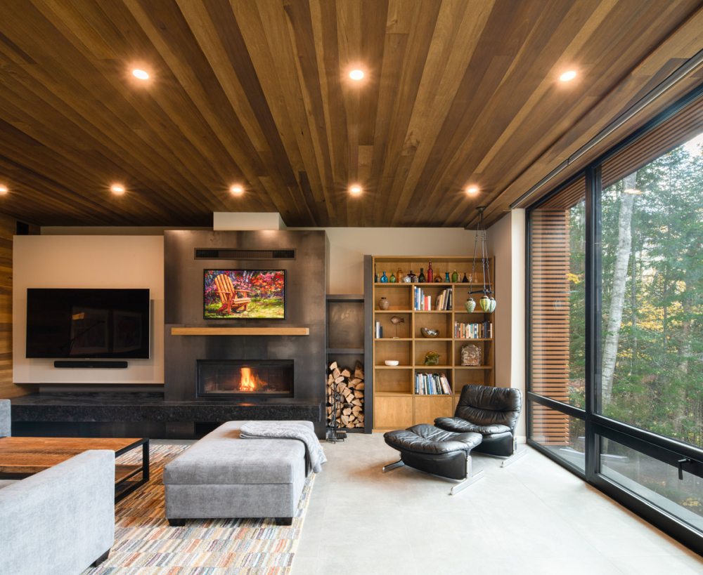 The living room shows off a built-in fireplace, upholstered and leather furniture, lights and a bright rug
