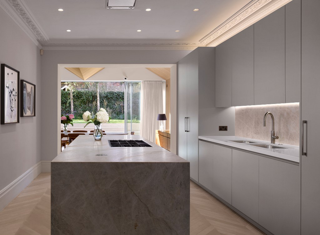The kitchen is minimalist, with sleek white cabintery and a marble kitchen island