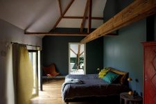 07 The bedroom is moody, with hunter green walls, bright textiles, wooen beams that add charm and a vintage feel