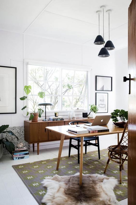 A stylish mid century modern home office with windows and a cluster of pendant lamps is a cool and airy space