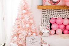 a blush Christmas tree with white ornaments, printed gift boxes, pink balloons in the fireplace and over it