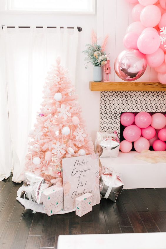 a blush Christmas tree with white ornaments, printed gift boxes, pink balloons in the fireplace and over it
