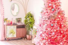 a bright pink Christmas tree with pastel and metallic ornaments and a large gold star topper for infusing your space with color