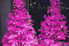 a duo of hot pink Christmas trees decorated with only lights is a fantastic idea for a modenr or minimalist holiday space