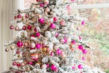 a flocked Christmas tree decorated with neutral, hot pink and blush ornaments and lights looks glam, chic and very modern