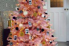 a pink Christmas tree with black and white ornaments, family photos, lights and ribbons is a cool modern solution