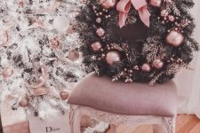 a refined and glam fir Christmas wreath dotted with pink ornaments and a large bow is a chic idea to bring a touch of glam