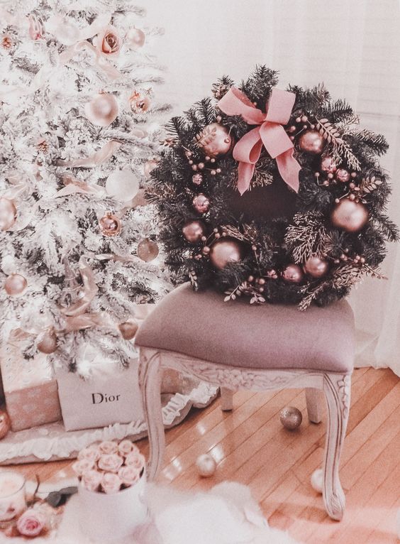 a refined and glam fir Christmas wreath dotted with pink ornaments and a large bow is a chic idea to bring a touch of glam
