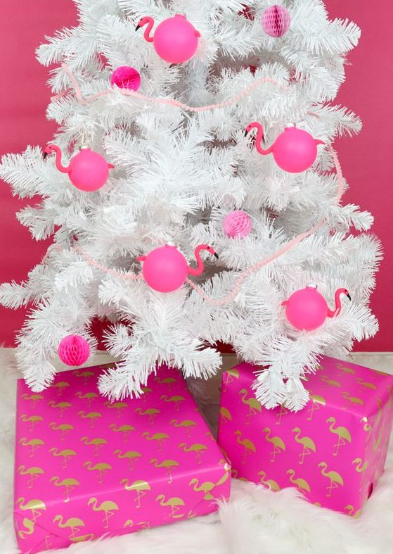 A white Christmas tree decorated with hot pink paper pompoms and flamingo shaped ornaments is a fun idea for a tropical holiday space