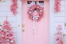pink Christmas outdoor decor with trees and silver and pink ornaments, a pink wreath and a garland and some ornaments
