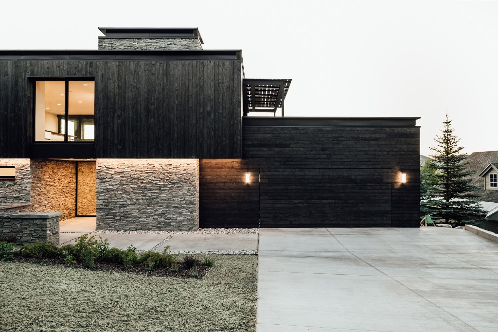 02 The exterior of the house is done with blackened wood and stone to connect it to the surroundings