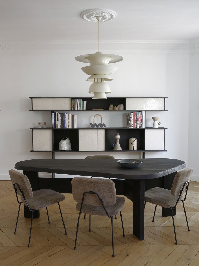 The dining space shows off a dark wooden table, some cool chairs and a refined storage piece at the wall