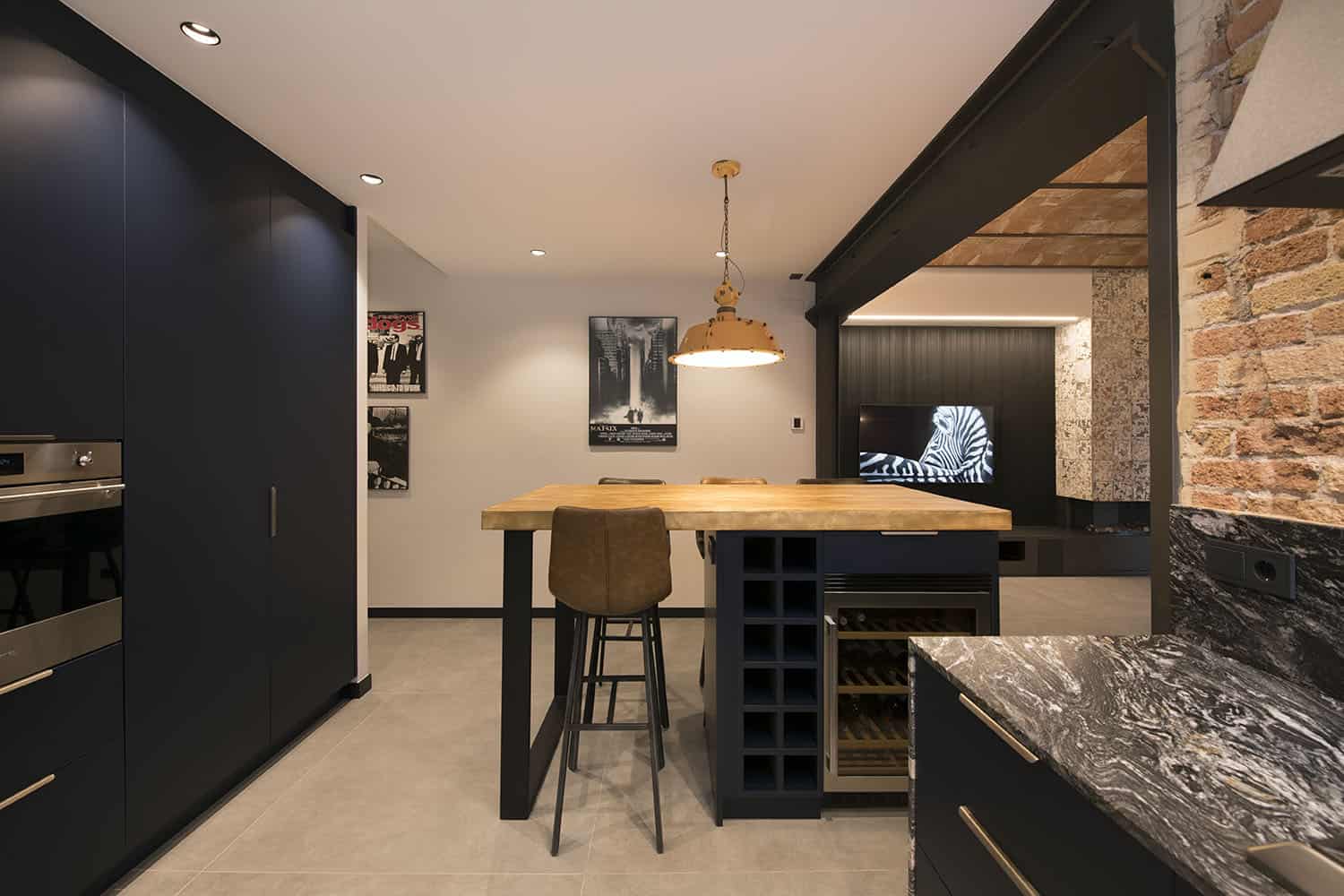 The kitchen island features wine storage, light stained butcherblock countertop and tall leather stools