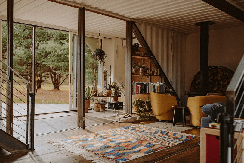 The foyer runs into a living area, which is done with boho rugs and bright furniture, with a hearth and a triangle shelf