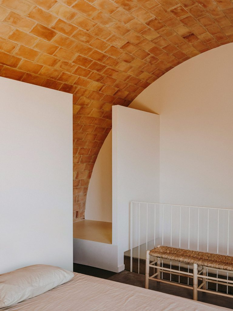 The main bedroom sits beneath an arched first floor and a very cool woven bench