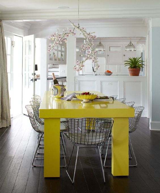a bright contemporary dining space with a neon yellow table and grey metal chairs plus a whimsical cherry blossom chandelier