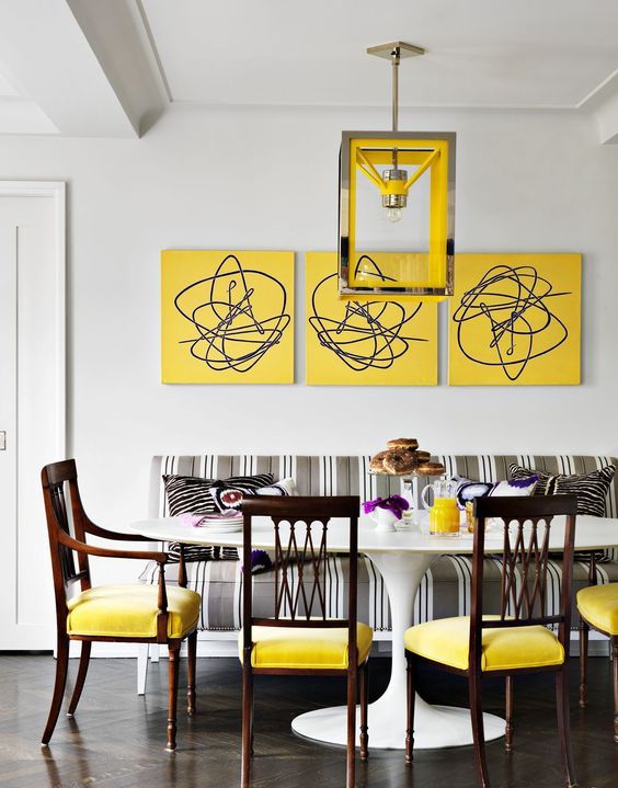 a bright dining room with a vintage feel - a bold yellow gallery wall, a grey striped sofa, yellow chairs and a catchy pendant lamp