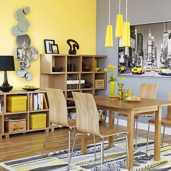 a bright grey and yellow dining room with a grey and a yellow accent wall, an open storage unit, a stylish dining set and lemon yellow pendant lamps