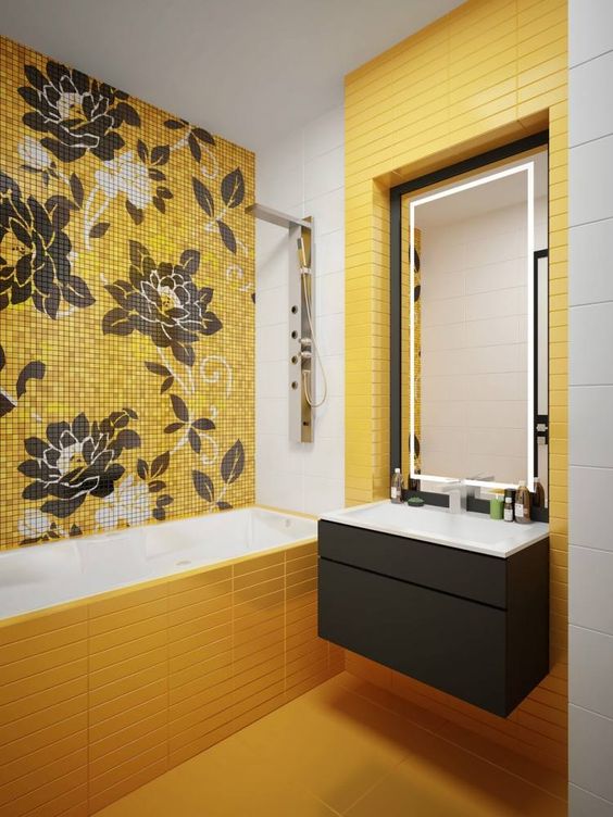 a bright modern bathroom with yellow tiles, a floral tile wall and a grey vanity plus lights for an accent