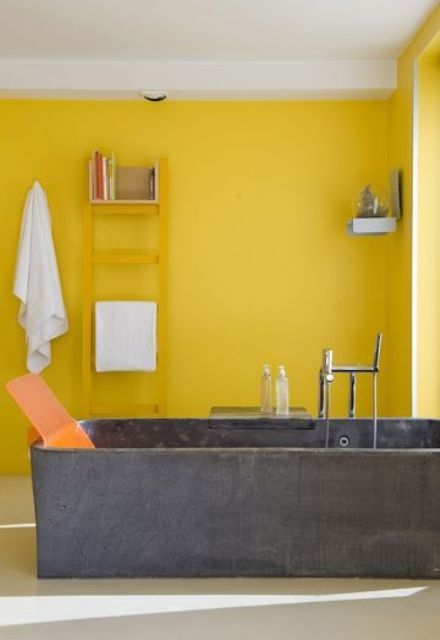 a bright yellow bathroom with a concrete tub, a yellow ladder, shelves and neutral textiles is very modern and bold