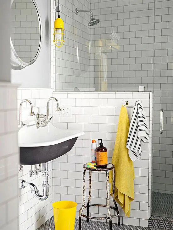 a chic vintage bathroom with white subway tiles, a grey sink, a vintage stool, bright yellow accents here and there