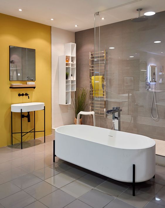 a contemporary bathroom with a grey wall and a yellow one, white appliances, a shower space and a couple of racks for storage