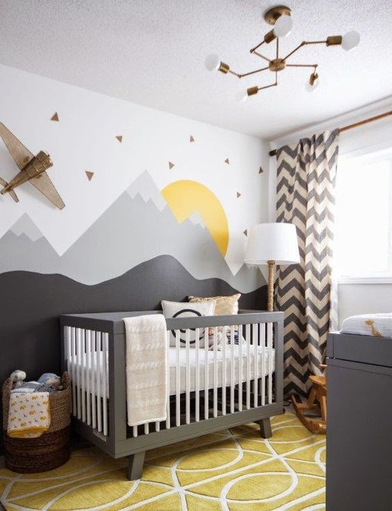 a cool mountain nursery with a moutain accent wall, grey furniture, a mustard rug, chevron curtains is veyr adventurous