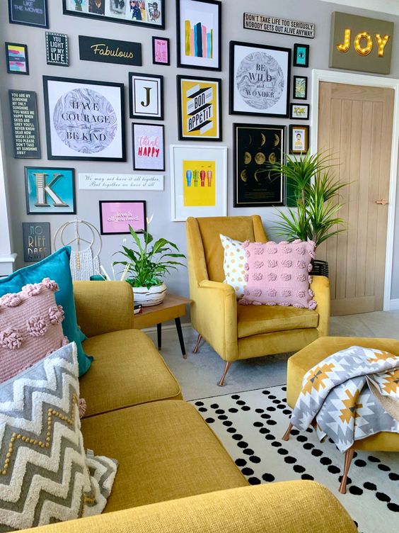 a fun and bright living room with a yellow sofa and chairs, printed pillows and blankets, a bold gallery wall and a marquee light