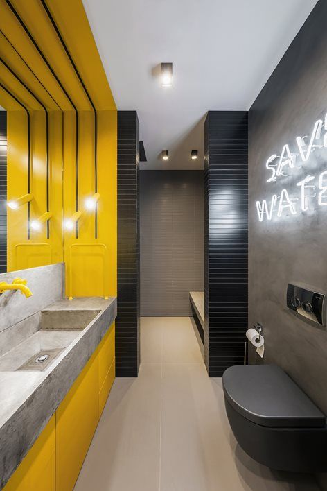 a minimalist bathroom with grey concrete walls, a bright yellow vanity zone and a concrete sink, neon and usual lights